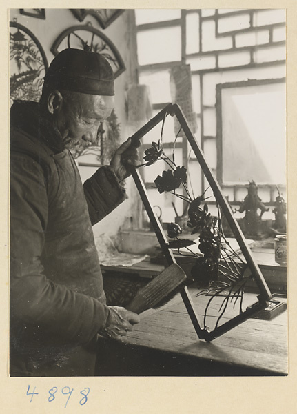 Man smoothing the edge of an iron picture with a brush in a workshop that makes iron pictures