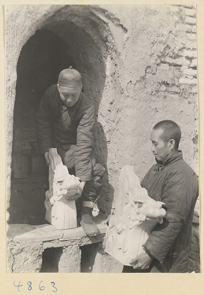 Men removing animal-shaped roof ornaments from a kiln at a tile and brick factory near Mentougou Qu