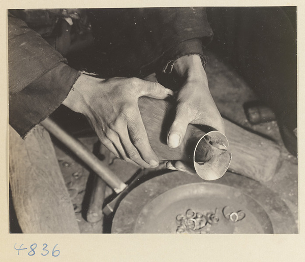 Coppersmith working on a pitcher in a workshop