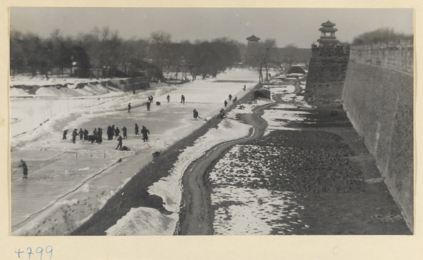 People cutting ice from a moat next to the city walls