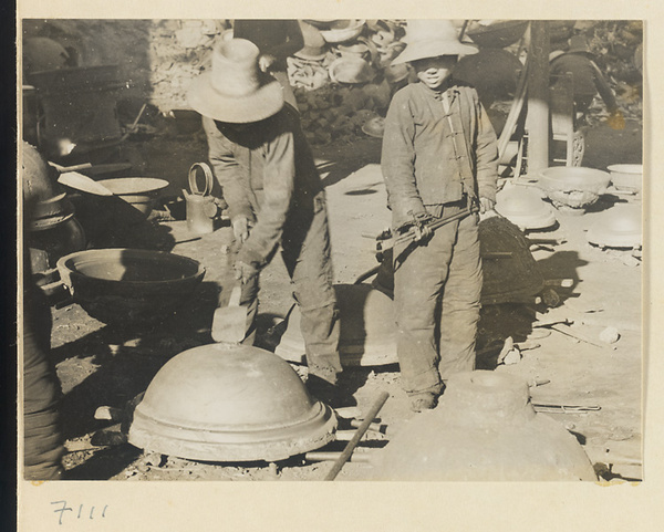 Boys removing an iron pot from a mold at a foundry near Mentougou Qu