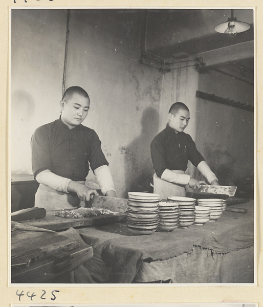 Kitchen of Niu Rou Wan, a Muslim grilled-beef restaurant, showing two men chopping food