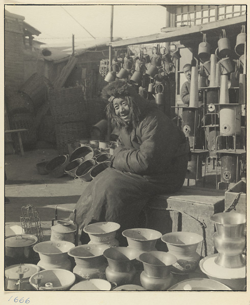 Man selling metal and ceramic household goods in front of shop