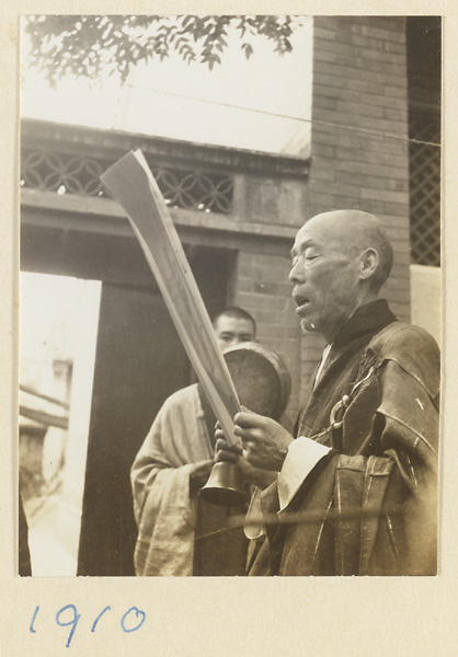 Buddhist monk with a bell reading a sutra during a funeral service