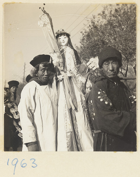 Member of a funeral procession carrying a paper figure of a female servant