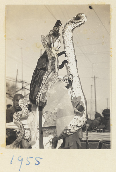 Member of a funeral procession carrying a paper figure riding on a crane