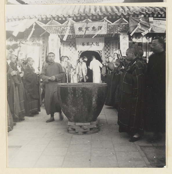 Mourners and Buddhist monks with musical instruments outside a funeral pavilion adorned with elegaic inscriptions