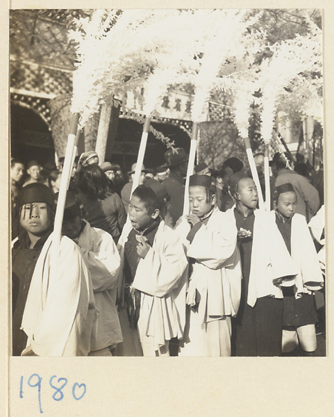 Boys carrying paper snow willows in a funeral procession