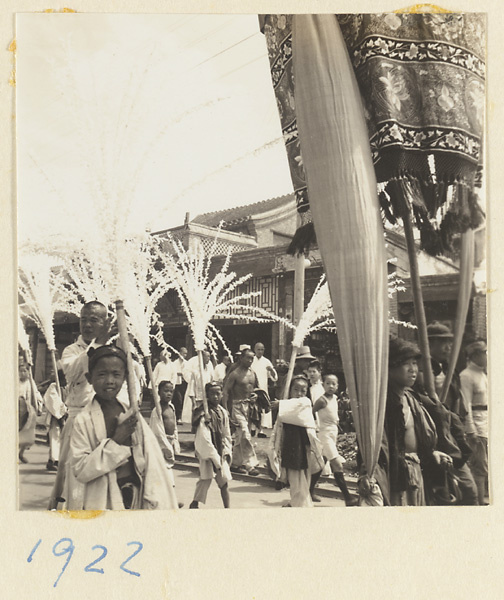 Members of a funeral procession carrying paper snow willows and umbrella