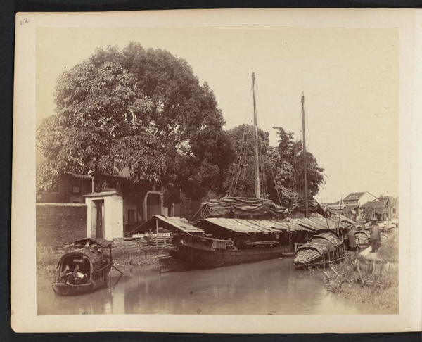 Sampans and Chinese two-masted sailboat docked on waterway between Shameen Island and north bank of Pearl River, Canton
