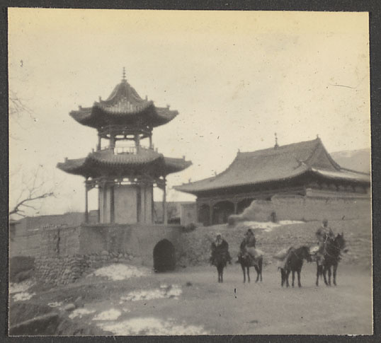 Men on horseback outside walled mosque