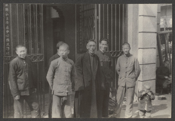 Men and boys in front of iron gate