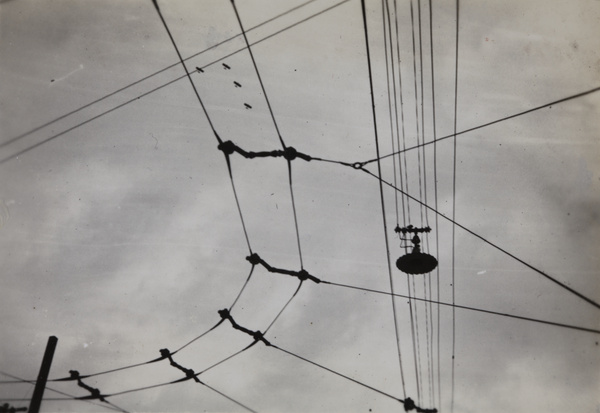 Four biplanes seen through overhead tram and electricity wires, Shanghai