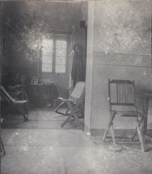 A man resting in a lightly furnished room, with a rocking chair
