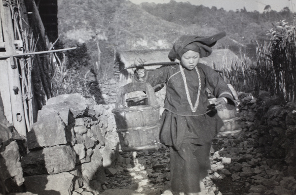 A woman carrying two wooden pails
