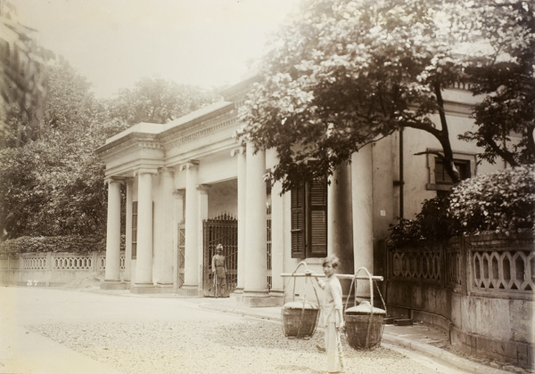 Man with a carrying pole in front of the entrance to Government House, Hong Kong