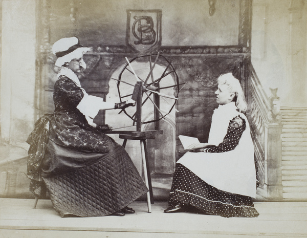 Two characters on stage, with a spinning wheel 