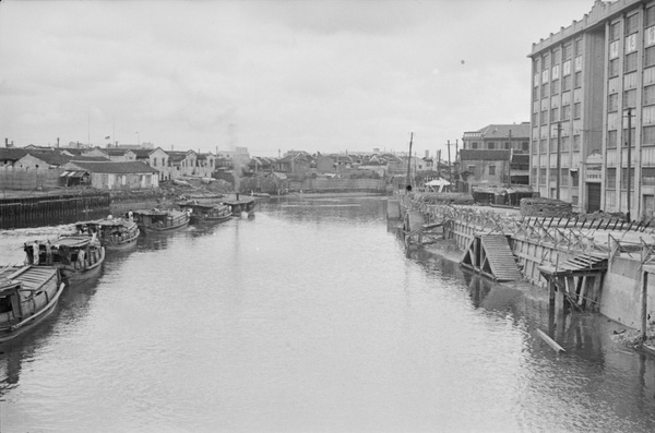 Boat train passing fortified jetty and Sihang warehouse, Soochow Creek, Shanghai