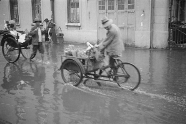 Rickshaw and delivery tricycle pass through flood waters, Shanghai
