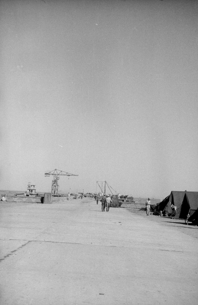 Soldiers and tents by a jetty with cranes