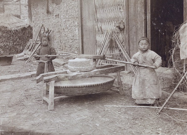 Children milling grain, at a farm