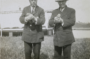 European men holding homing pigeons
