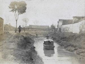 A launch in a creek, with bridge and buildings