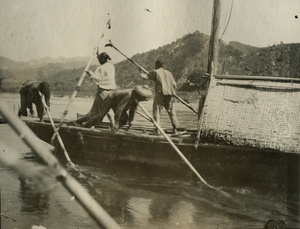 Team of boatmen working with poles