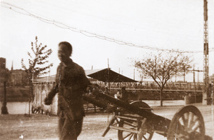 A man with a wheelbarrow near a swing bridge, Tianjin