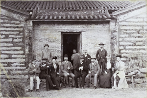 A group of Europeans sitting underneath the roof in front of a doorway
