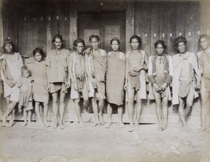 Barefooted labourers standing in front of a door 