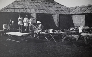 Shanghai Rowing Club members resting by a matshed boat house