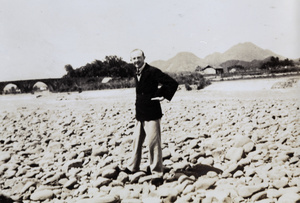 A man standing on stones by a river