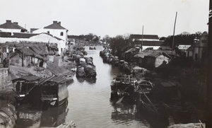 Sampans moored along a waterway by a city wall