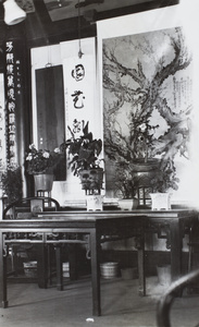 Inscribed column, scrolls, potted plants and tables