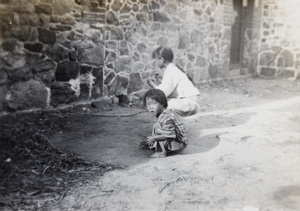 Two children playing 'Five Stones' by a house, Weihai (威海)