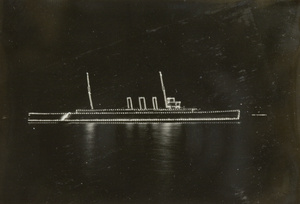 A warship at night, lit up in profile