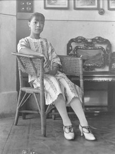 A young woman seated on a cane chair