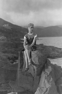 Woman in swimsuit sitting on a rock