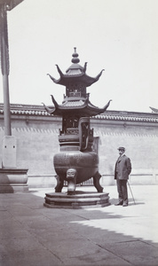 Man wearing a boater hat standing beside a censer