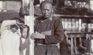 Two boys beside a man holding a split piece of bamboo