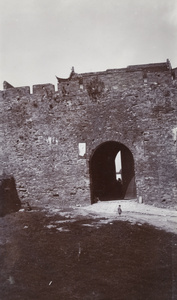 A child by a half-open gate and city wall