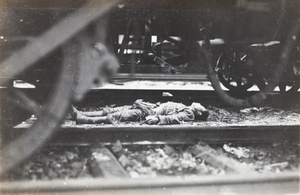A corpse lying beside rolling stock and railway tracks