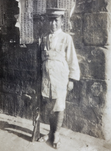 A Chinese soldier standing beside some posters on a wall