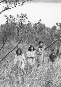 Kristine and Patricia Thoresen, an unidentified young woman, and Jim Hutchinson in a wooded area above a Castle Peak Road beach, Hong Kong