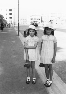 Kristine and Patricia Thoresen dressed up in hand-smocked frocks, ringlets and hats, Prince Edward Road, Kowloon, Hong Kong