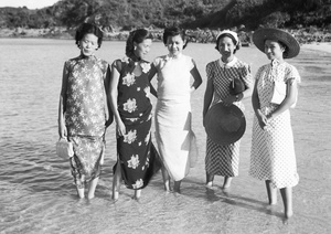 Unidentified wedding guests, Maggie Henderson and Lucy Hutchinson, ankle deep in shallow water at a beach, Hong Kong
