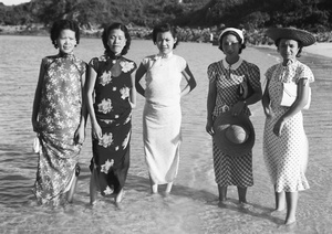 Unidentified wedding guests, Maggie Henderson and Lucy Hutchinson, ankle deep in shallow water at a beach, Hong Kong
