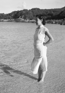 Unidentified woman, standing barefoot on a beach, Hong Kong