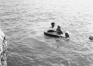 Unidentified people swimming and playing with an inflated inner tube, Hong Kong